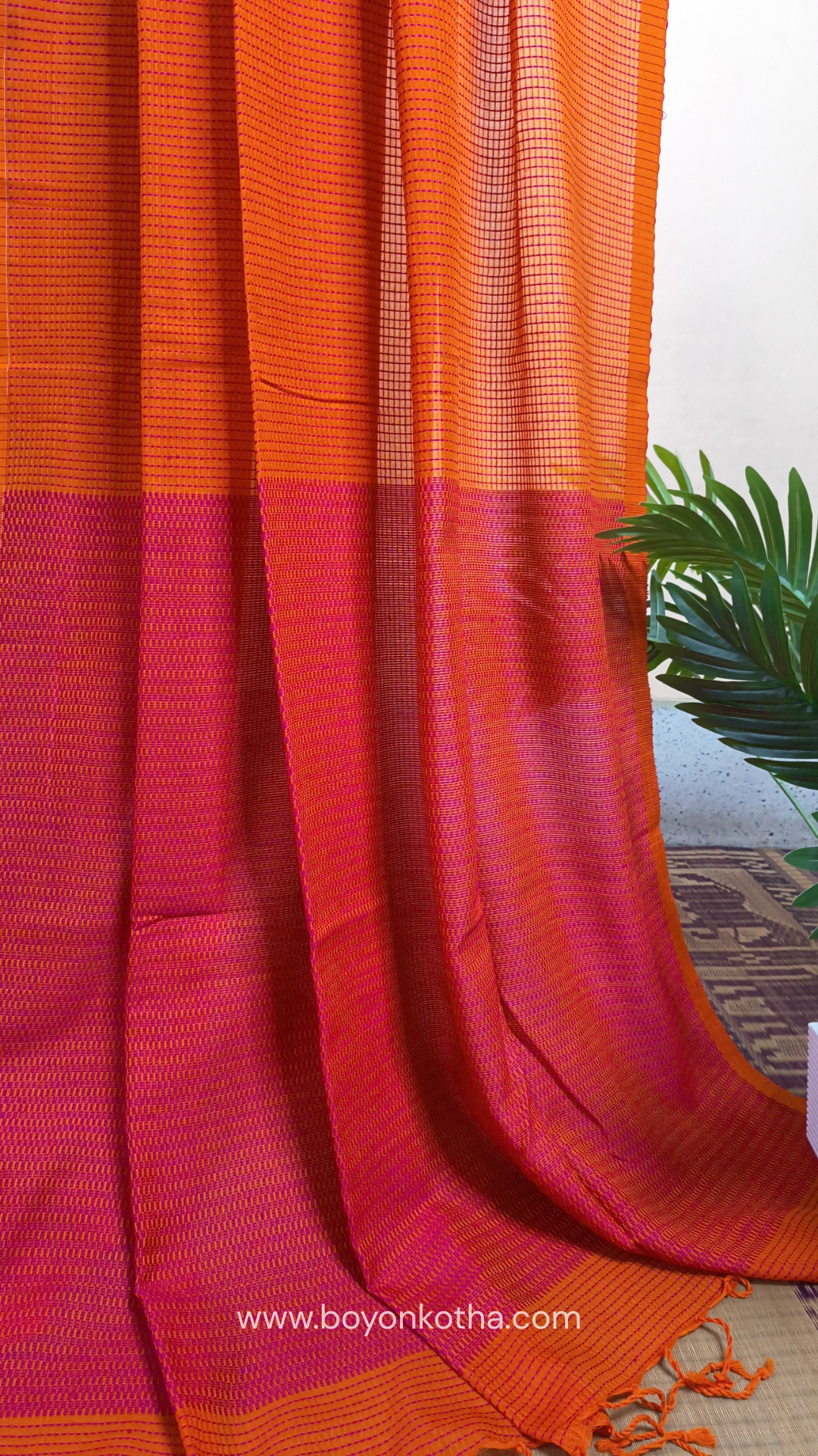 Orange handloom cotton saree with a kantha inspired weave in rani pink throughout, finished with tassels in the palla. Ideal for festivals & cultural gatherings