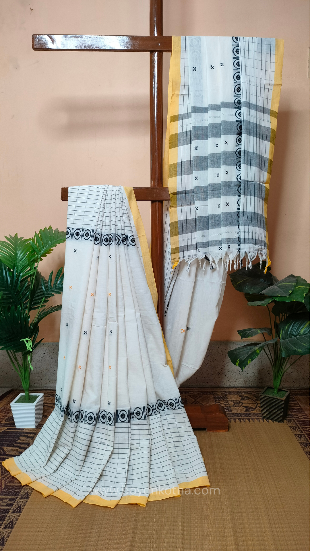 White Dhonekhali handloom cotton saree featuring a delicate yellow border and intricate woven black and yellow motifs. 