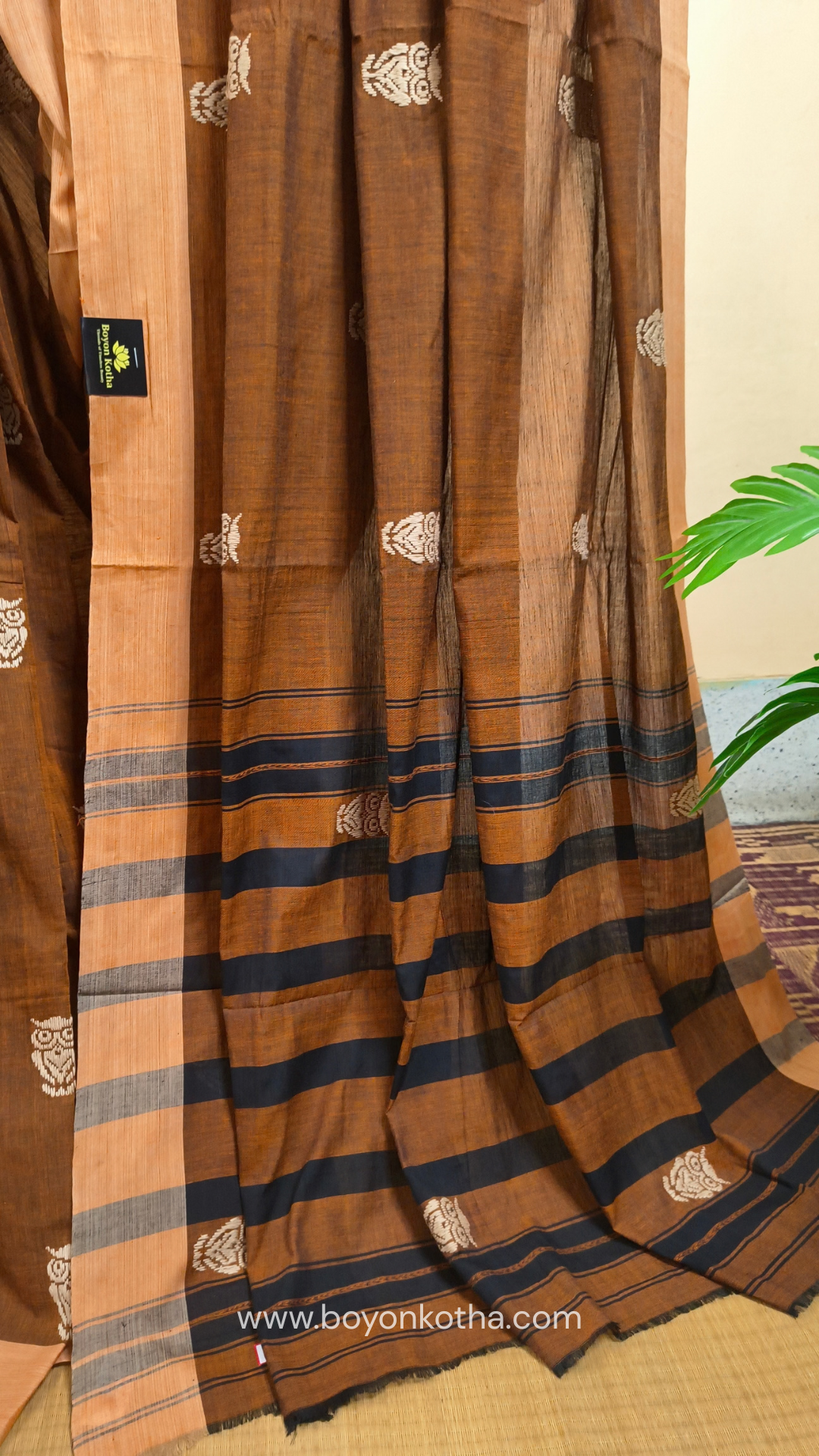 Rust Dhonekhali handloom cotton saree adorned with woven owl motifs in beige across the body and pallu. Perfect for casual gatherings and everyday elegance.