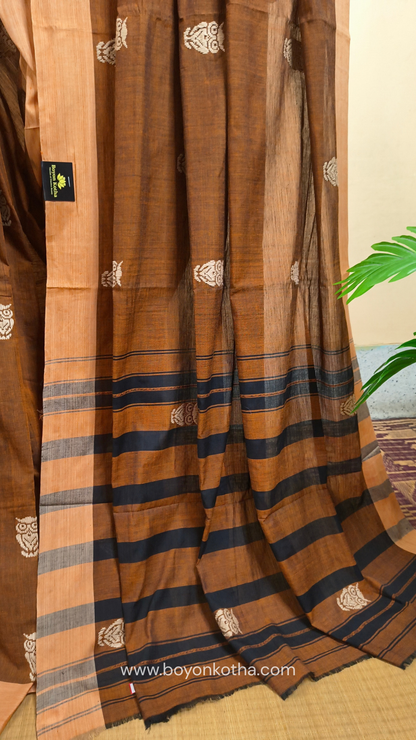 Rust Dhonekhali handloom cotton saree adorned with woven owl motifs in beige across the body and pallu. Perfect for casual gatherings and everyday elegance.