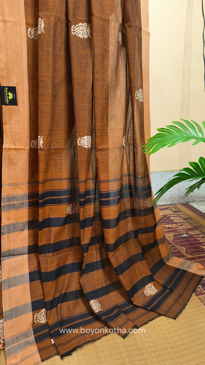 Rust Dhonekhali handloom cotton saree adorned with woven owl motifs in beige across the body and pallu. Perfect for casual gatherings and everyday elegance.