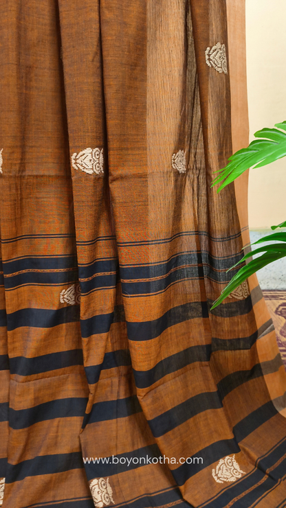 Rust Dhonekhali handloom cotton saree adorned with woven owl motifs in beige across the body and pallu. Perfect for casual gatherings and everyday elegance.