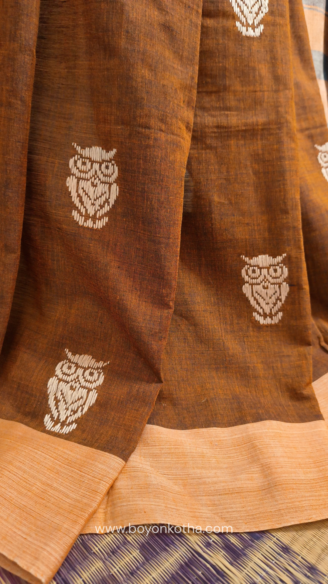 Rust Dhonekhali handloom cotton saree adorned with woven owl motifs in beige across the body and pallu. Perfect for casual gatherings and everyday elegance.