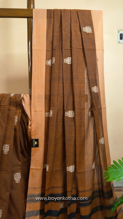 Rust Dhonekhali handloom cotton saree adorned with woven owl motifs in beige across the body and pallu. Perfect for casual gatherings and everyday elegance.