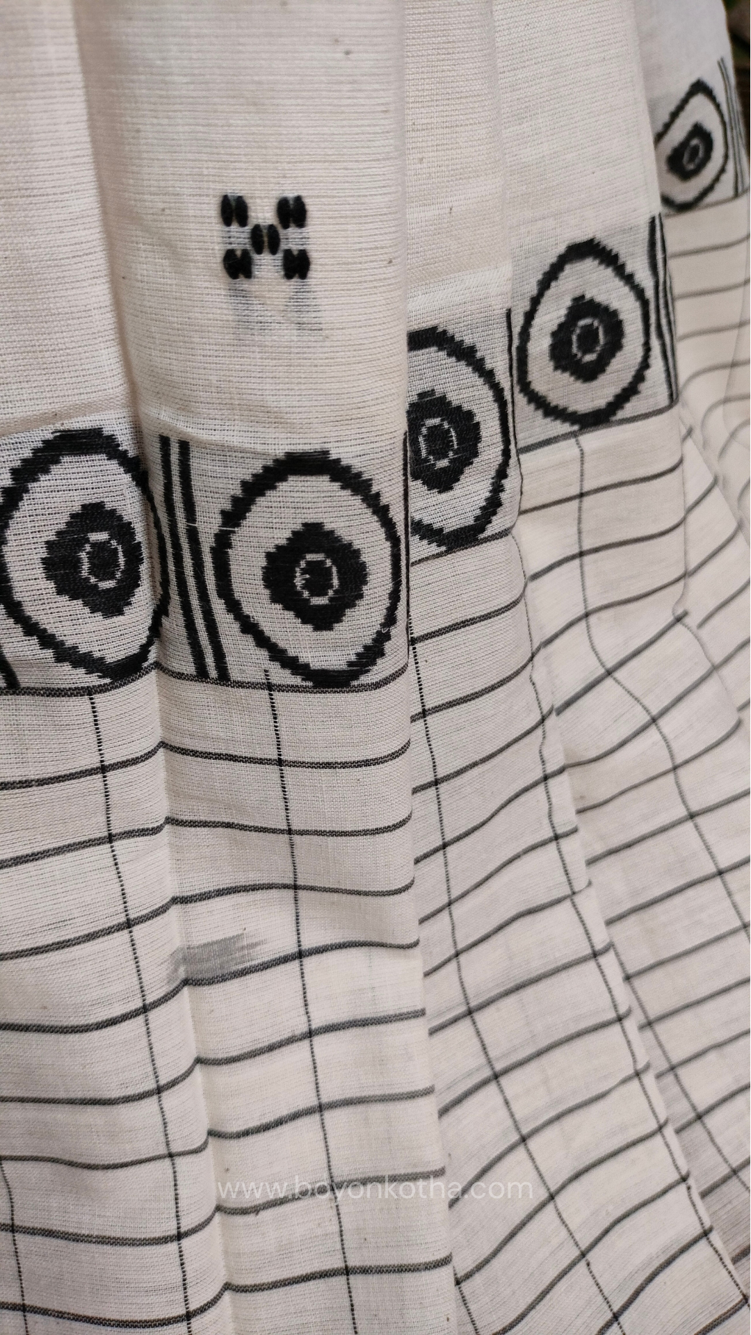 White Dhonekhali handloom cotton saree featuring a delicate yellow border and intricate woven black and yellow motifs. 