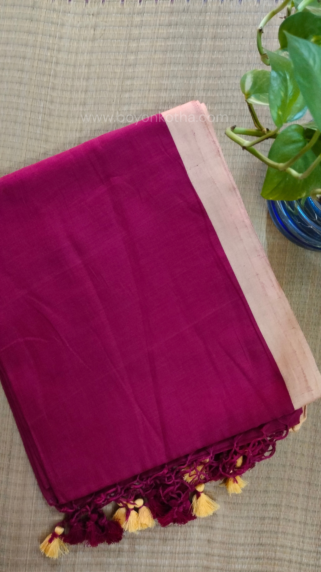 Maroon handwoven mul cotton saree with beige border, pallu ending in tassels. Plain handloom saree from Bengal.