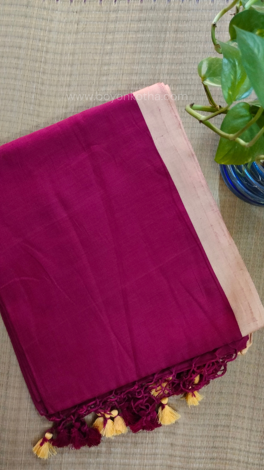 Maroon handwoven mul cotton saree with beige border, pallu ending in tassels. Plain handloom saree from Bengal.
