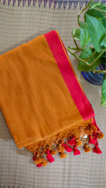 Mustard yellow handwoven mul cotton saree with red border, pallu ending in tassels. Plain handloom mustard yellow saree from Bengal.