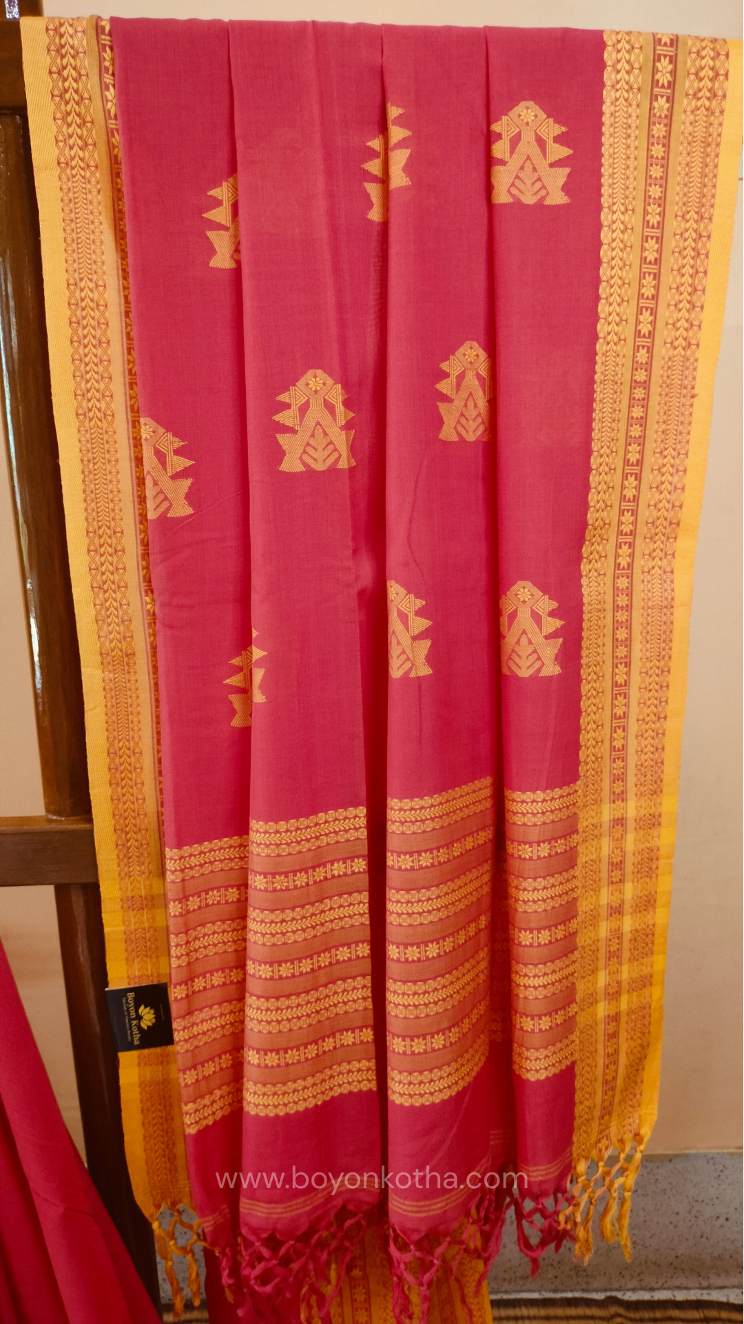 Pink handwoven mercerized cotton saree with Manipuri-inspired thread work pattern in yellow. Durable, breathable Bengal handloom saree for festive wear.