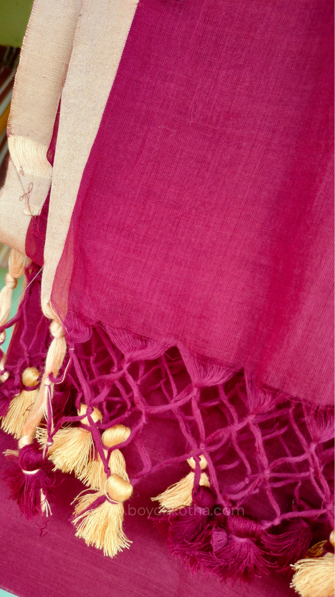 Maroon handwoven mul cotton saree with beige border, pallu ending in tassels. Plain handloom saree from Bengal.