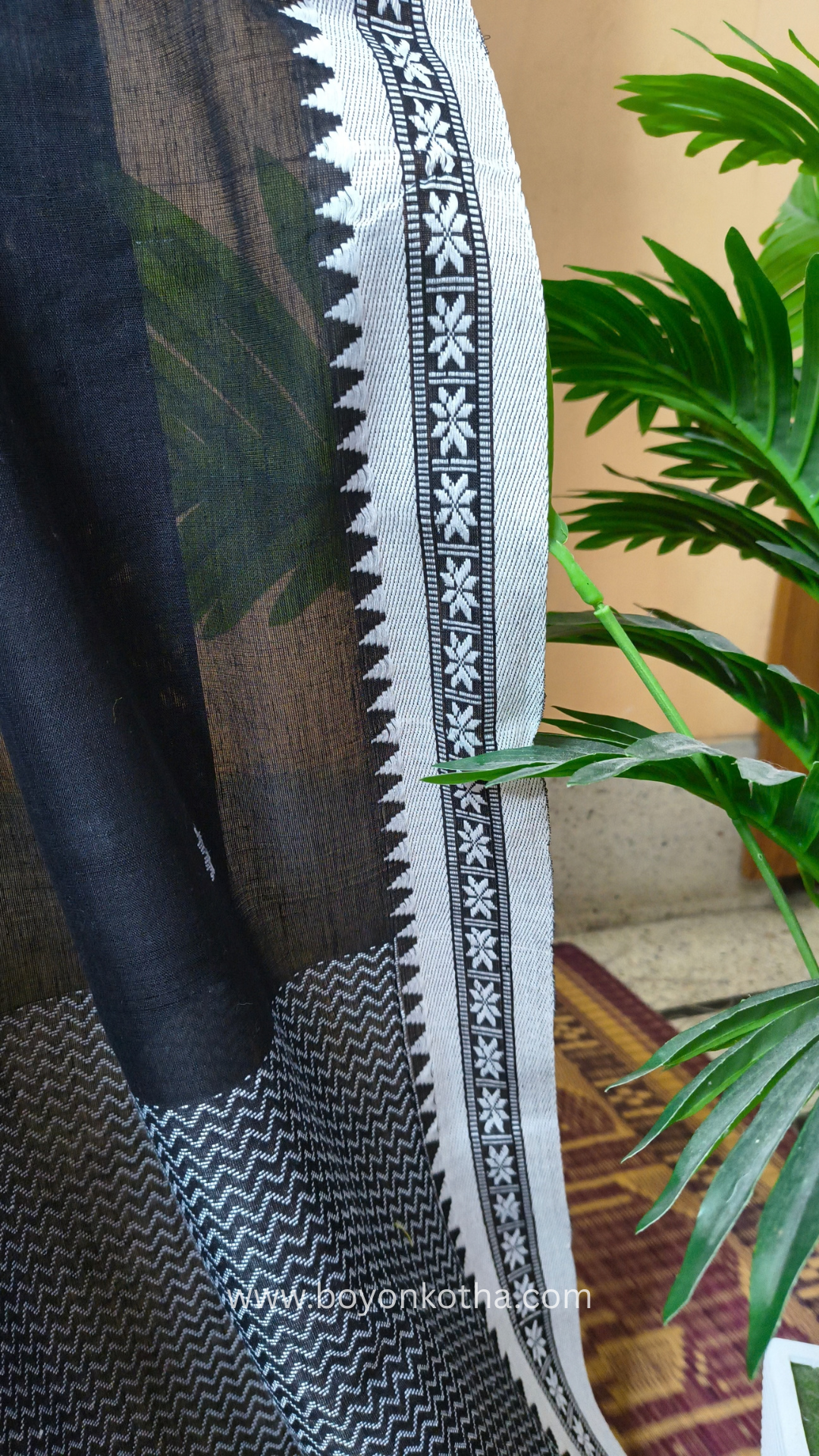 Black handloom cotton saree with white woven jamdani-inspired jacquard butis and nakshi border. Perfect for festivals and cultural gatherings.
