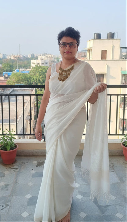 Model in a white mul cotton saree with jamdani motif standing in a balcony