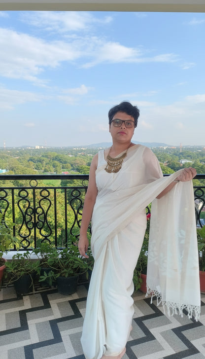 Woman in white mul cotton saree with jamdani motifs standing in a balcony
