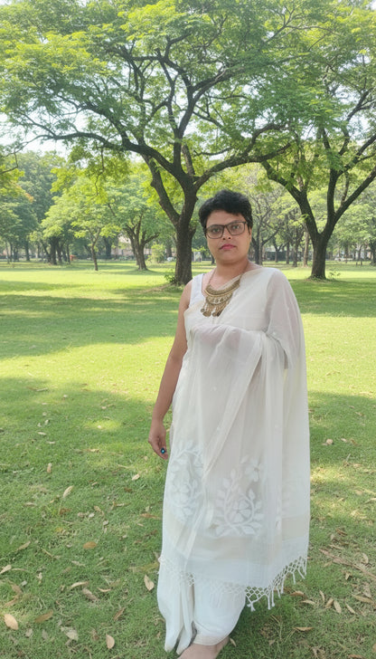 Woman wearing white mul cotton saree with jamdani motifs standing in a park