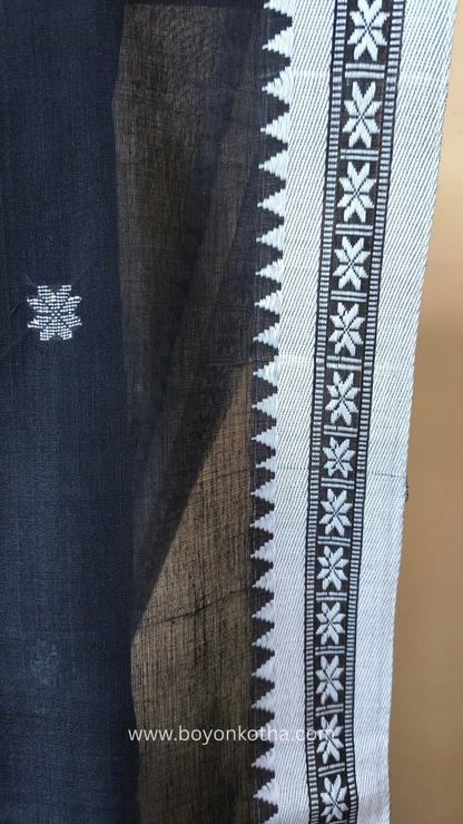 Black handloom cotton saree with white woven jamdani-inspired jacquard butis and nakshi border. Perfect for festivals and cultural gatherings.