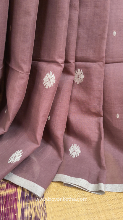 Mauvish Brown buttery soft handloom cotton saree, with jamdani inspired handloom jacquard woven butas all over and braided tassels. Ideal for festive mornings 