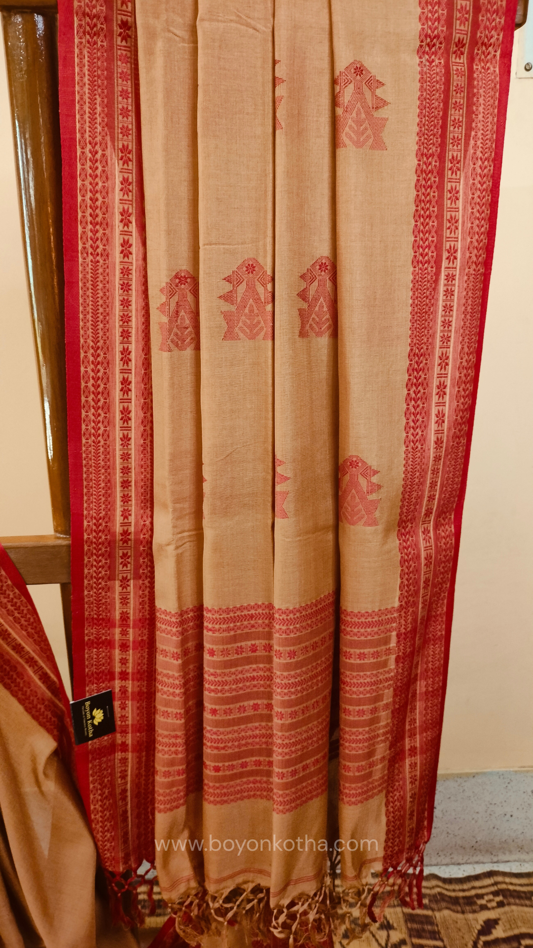 Beige handwoven mercerized cotton saree with Manipuri-inspired thread work pattern in red. Durable, breathable Bengal handloom saree for festive wear.