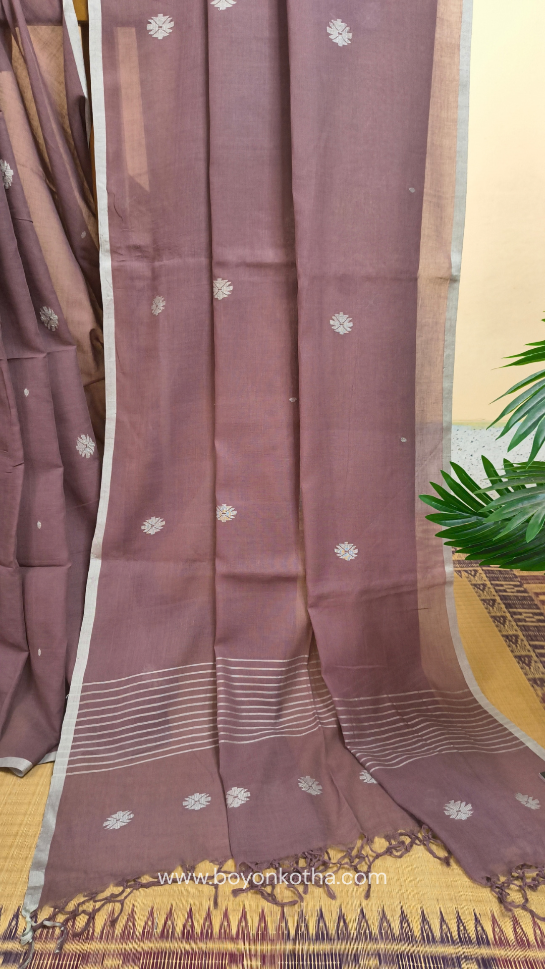 Mauvish Brown buttery soft handloom cotton saree, with jamdani inspired handloom jacquard woven butas all over and braided tassels. Ideal for festive mornings 