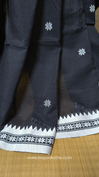 Black handloom cotton saree with white woven jamdani-inspired jacquard butis and nakshi border. Perfect for festivals and cultural gatherings.