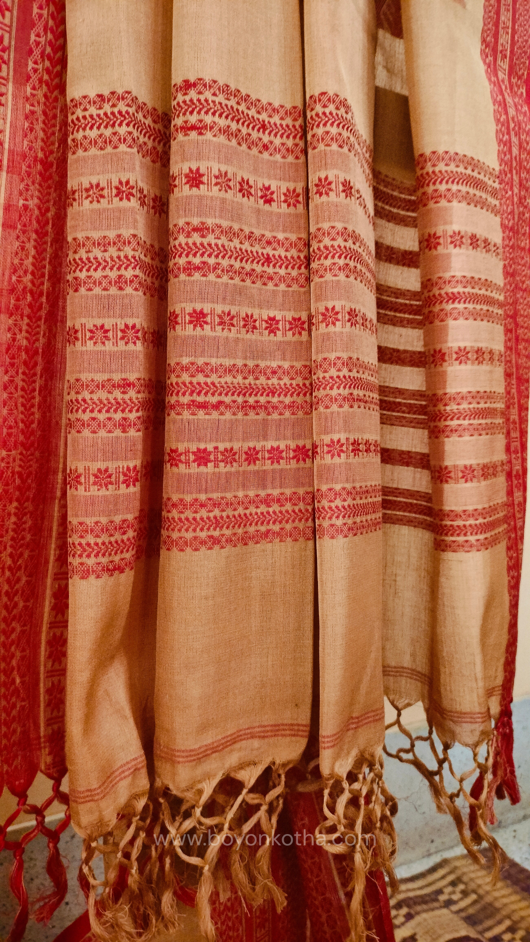 Beige handwoven mercerized cotton saree with Manipuri-inspired thread work pattern in red. Durable, breathable Bengal handloom saree for festive wear.