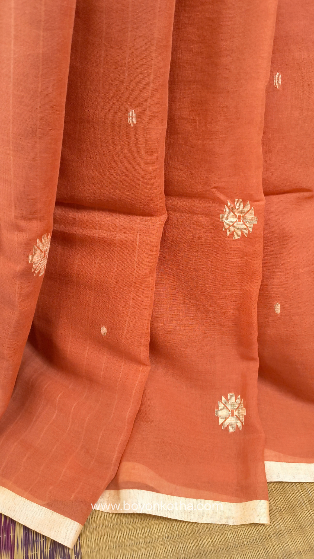 Orangish peach buttery soft handloom cotton saree, with jamdani inspired handloom jacquard woven butas all over and braided tassels. Ideal for festive mornings 