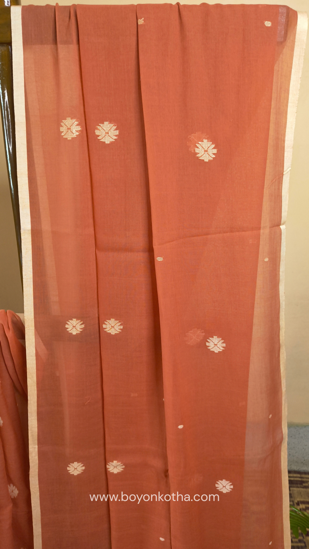 Orangish peach buttery soft handloom cotton saree, with jamdani inspired handloom jacquard woven butas all over and braided tassels. Ideal for festive mornings 