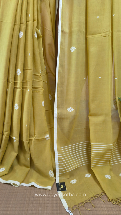Greenish yellow buttery soft handloom cotton saree, with jamdani inspired handloom jacquard woven butas all over and braided tassels. Ideal for festive mornings 