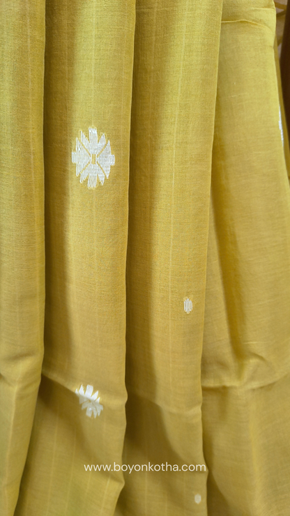 Greenish yellow buttery soft handloom cotton saree, with jamdani inspired handloom jacquard woven butas all over and braided tassels. Ideal for festive mornings 
