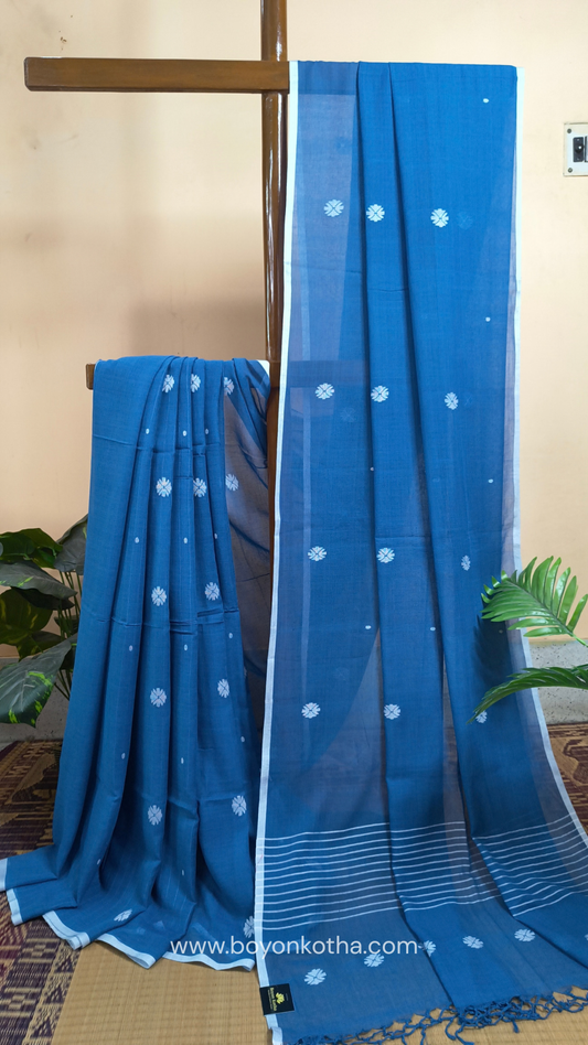 Blue buttery soft handloom cotton saree, with jamdani inspired handloom jacquard woven butas all over and braided tassels. Ideal for festive mornings 
