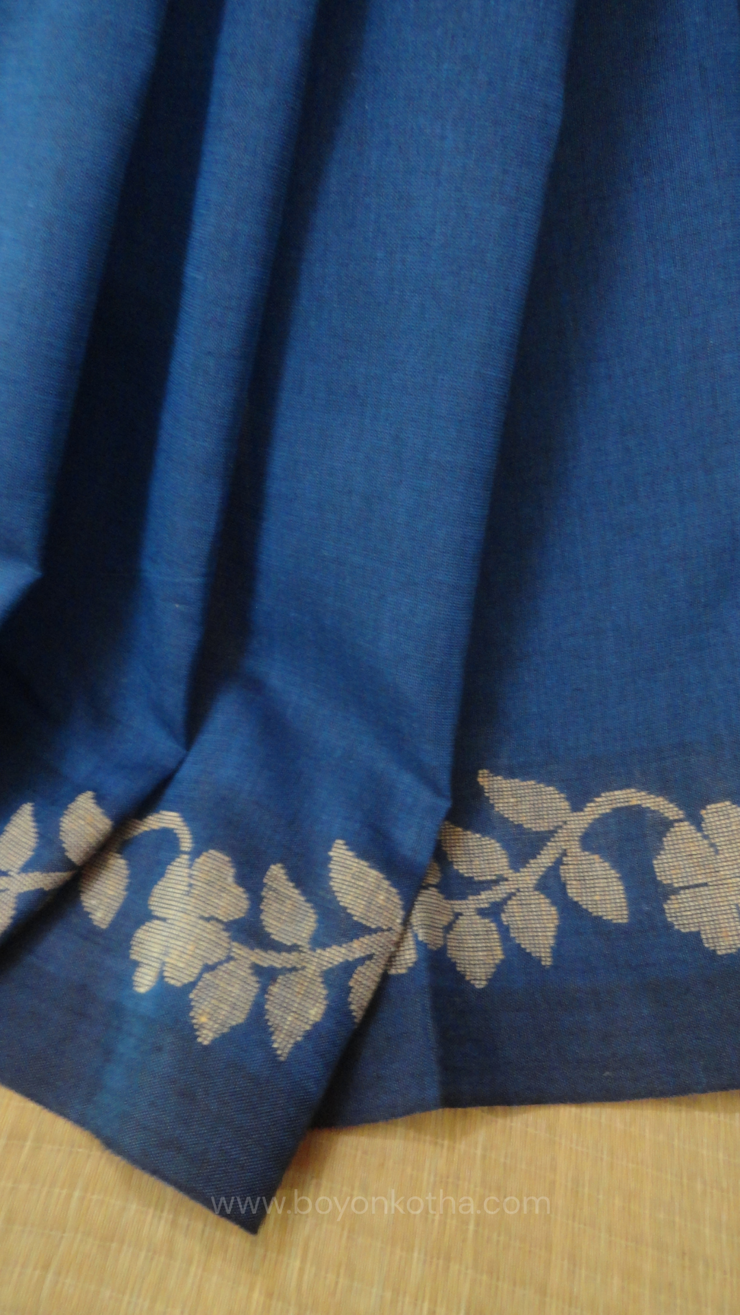 Blue handwoven cotton saree, with woven beige floral vines running across the border till the pallu; bengal handloom, blue saree