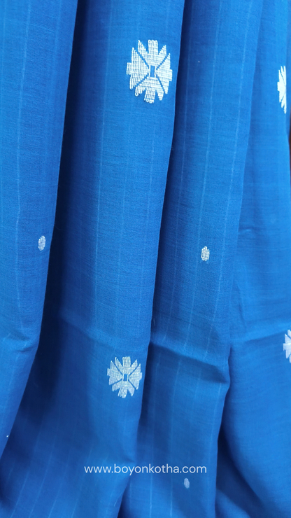Blue buttery soft handloom cotton saree, with jamdani inspired handloom jacquard woven butas all over and braided tassels. Ideal for festive mornings 