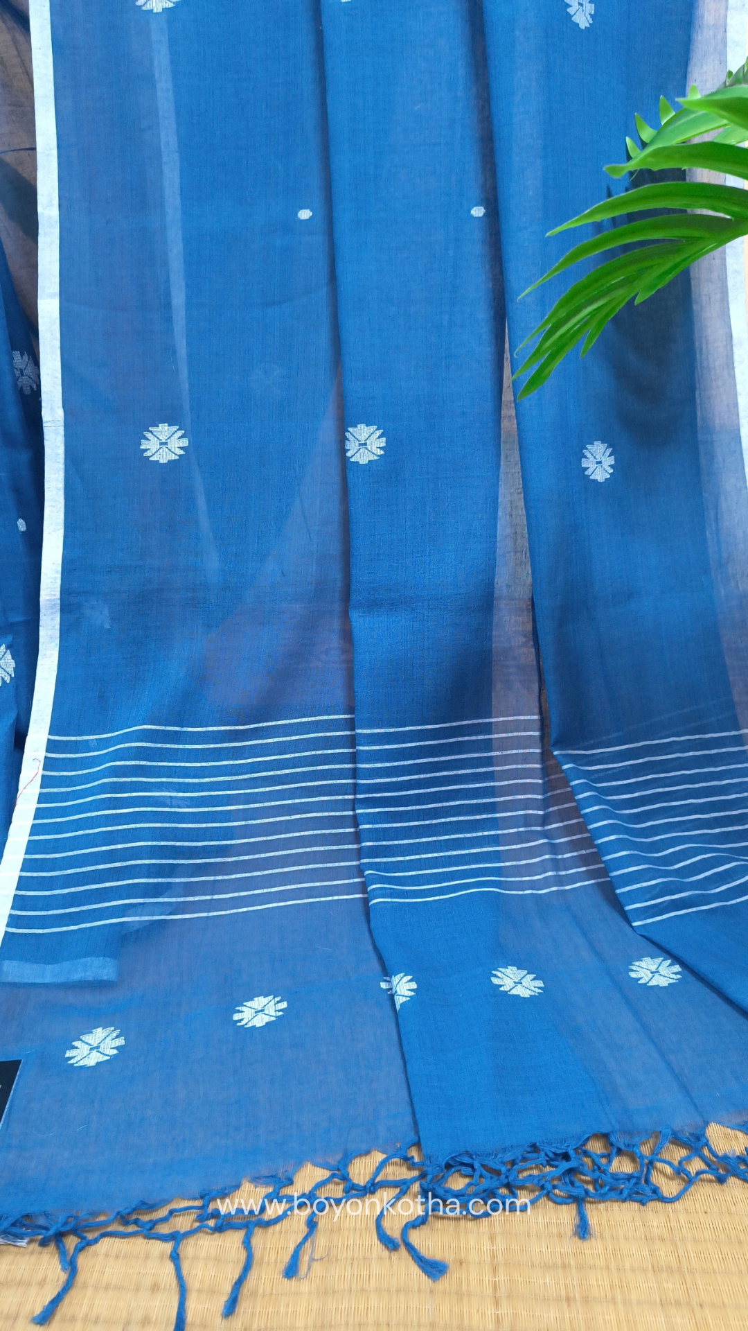 Blue buttery soft handloom cotton saree, with jamdani inspired handloom jacquard woven butas all over and braided tassels. Ideal for festive mornings 