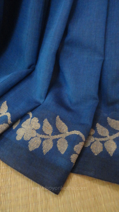 Blue handwoven cotton saree, with woven beige floral vines running across the border till the pallu; bengal handloom, blue saree