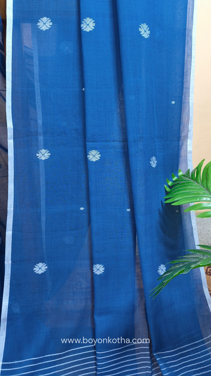Blue buttery soft handloom cotton saree, with jamdani inspired handloom jacquard woven butas all over and braided tassels. Ideal for festive mornings 