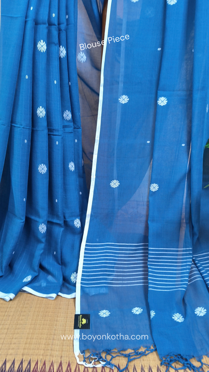 Blue buttery soft handloom cotton saree, with jamdani inspired handloom jacquard woven butas all over and braided tassels. Ideal for festive mornings 