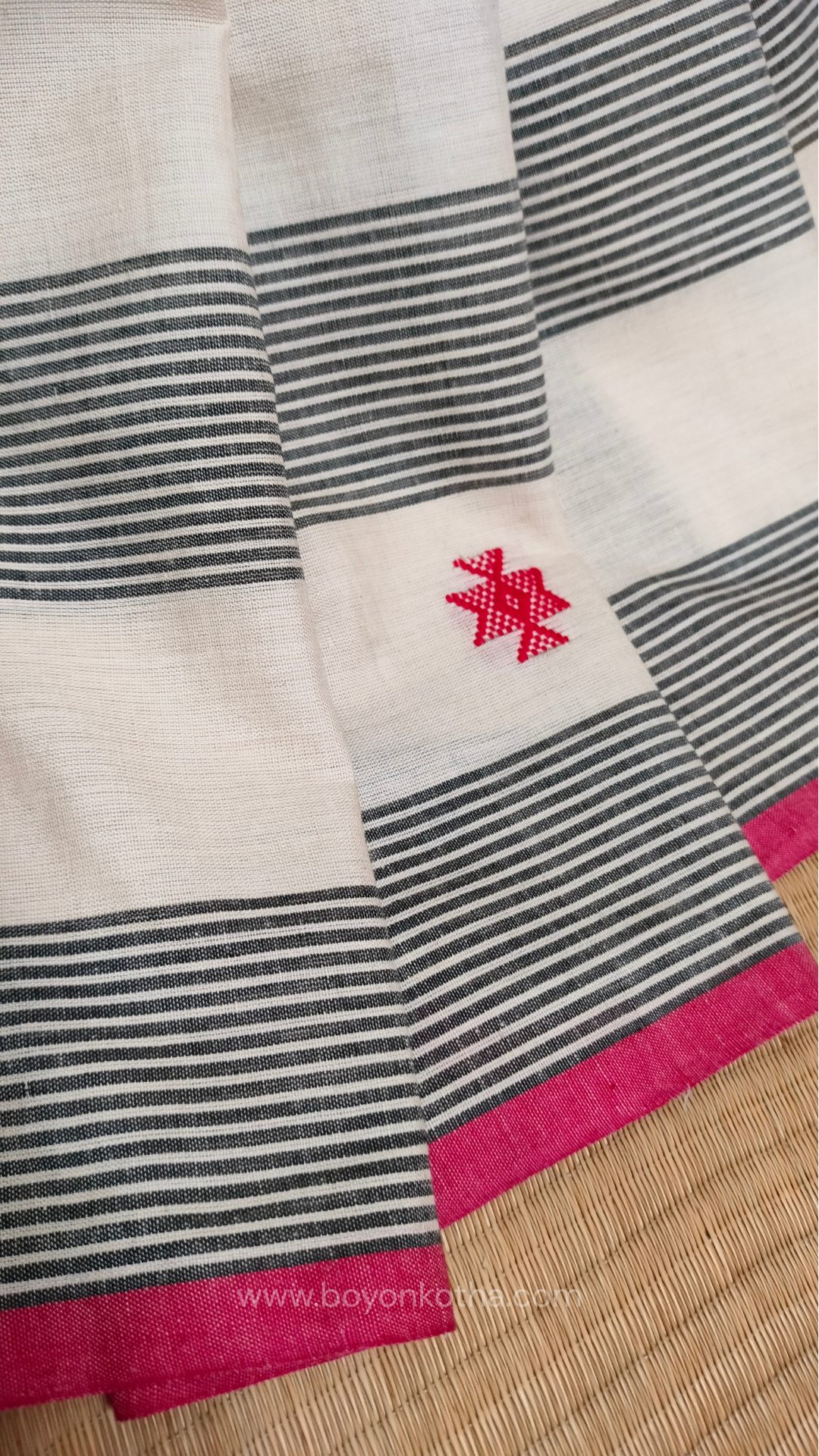Elegant off-white Dhonekhali handloom cotton saree featuring striking black stripes and woven red and black motifs.