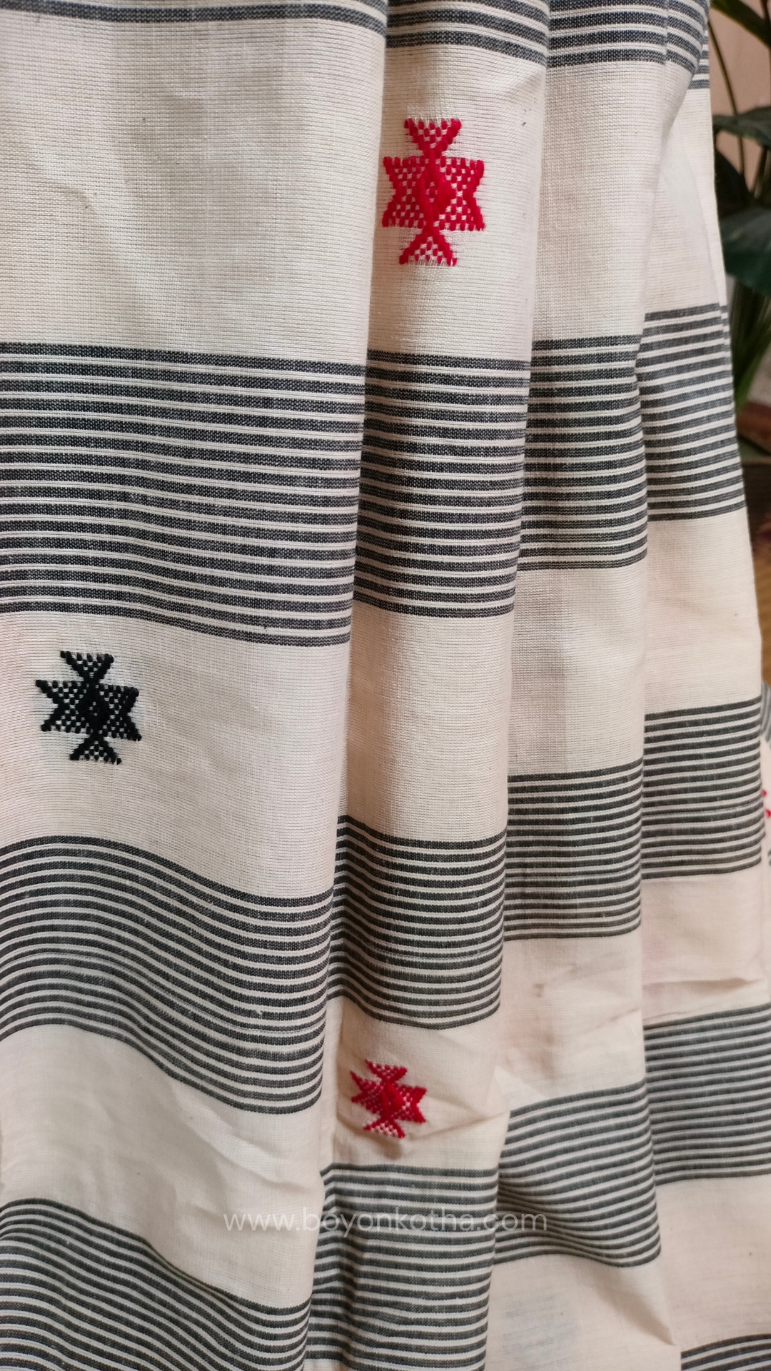 Elegant off-white Dhonekhali handloom cotton saree featuring striking black stripes and woven red and black motifs.