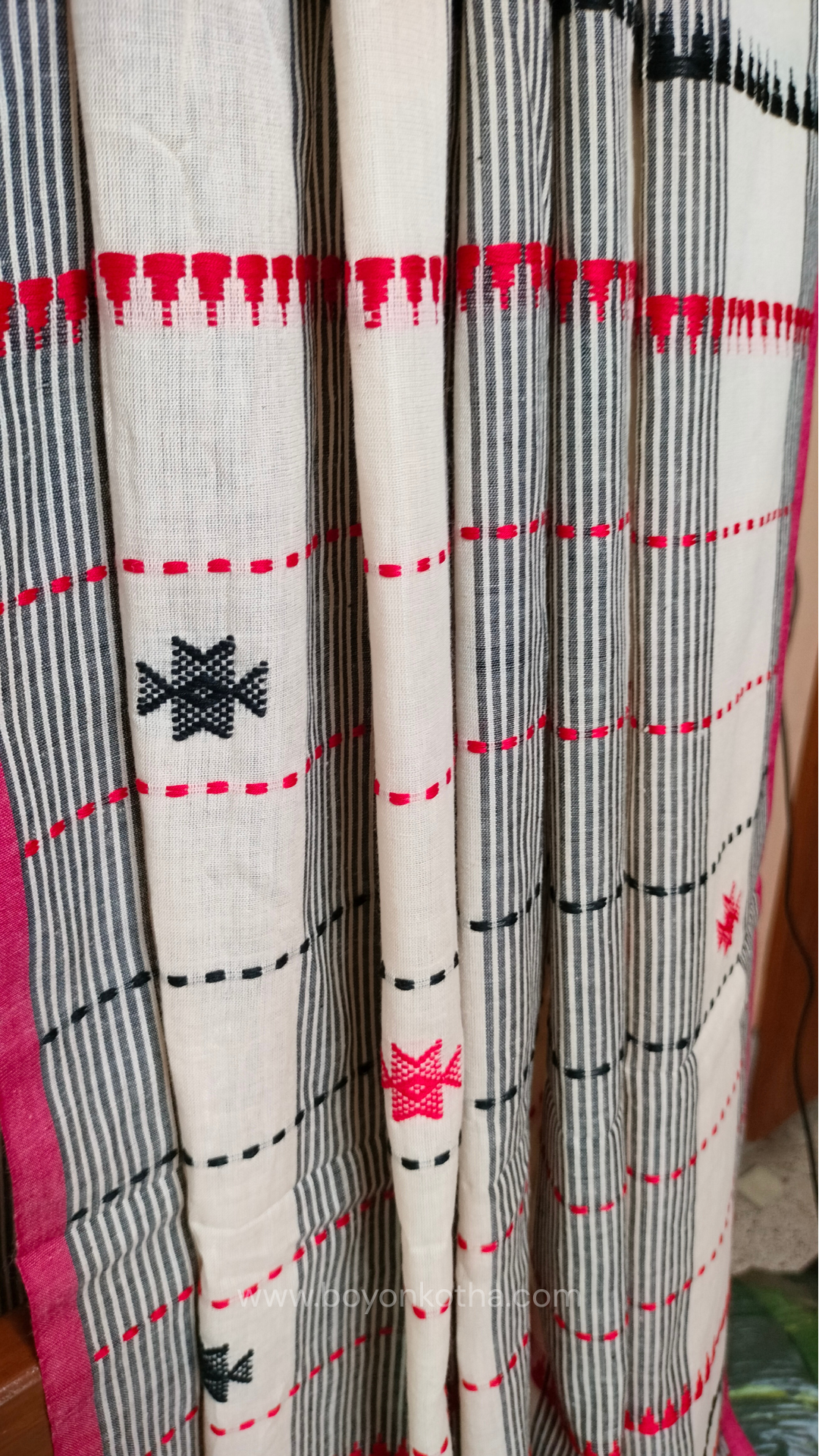Elegant off-white Dhonekhali handloom cotton saree featuring striking black stripes and woven red and black motifs.