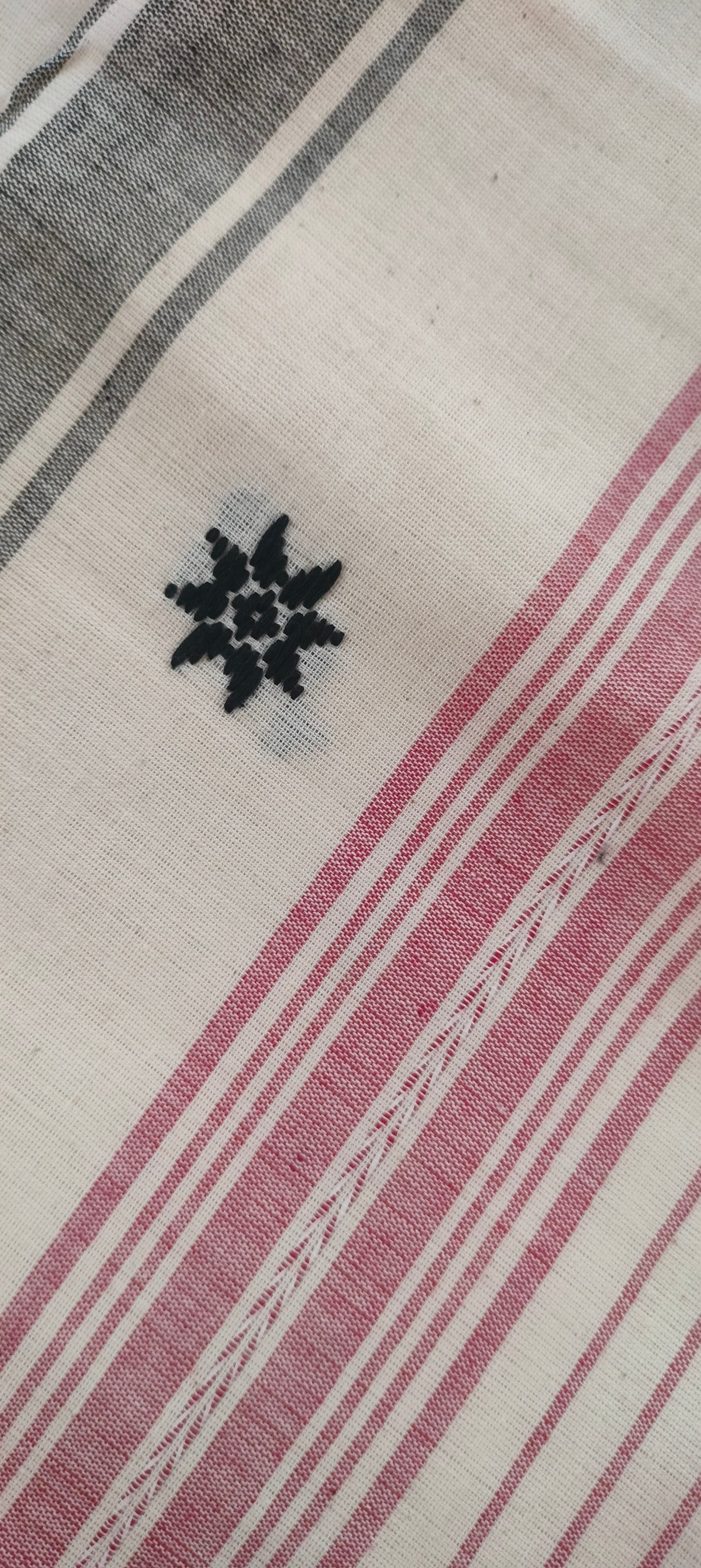 Close-up of pallu showing black motif of a red, black and white Dhonekhali cotton saree.