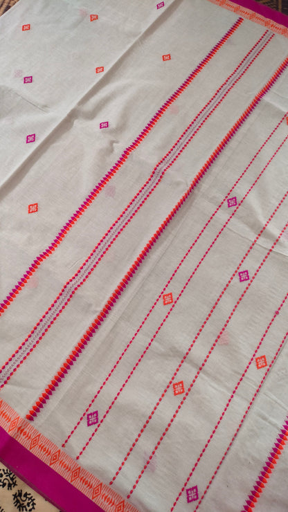 A white Dhonekhali handloom cotton saree with orange and pink woven motifs and bands on the saree. The border of the saree is pink with the inner edge having orange motifs.