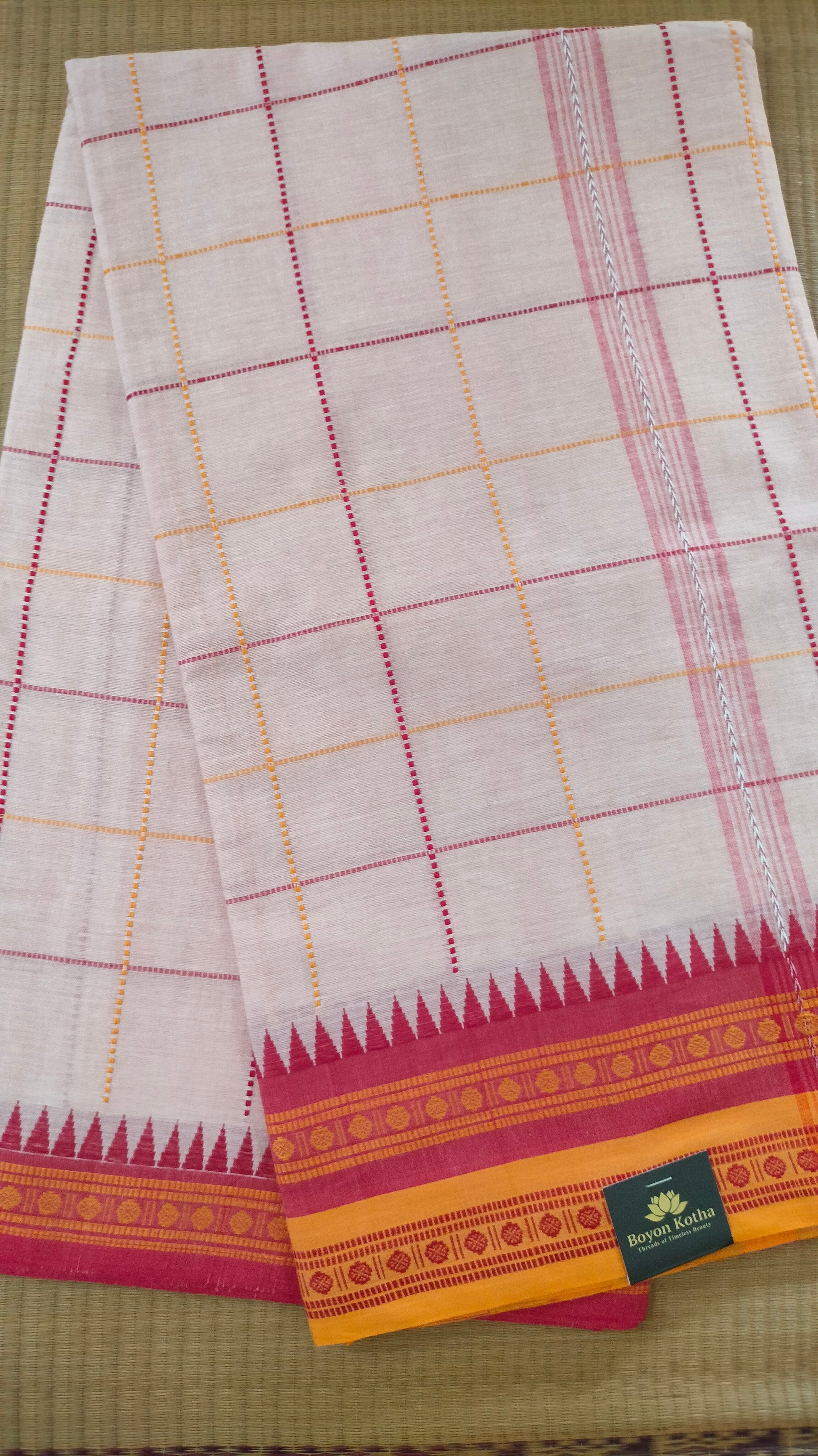 Off-white Dhonekhali handloom cotton saree with woven red and yellow check patterns throughout the body. Ideal for festive, semi-festive gatherings and refined everyday wear.