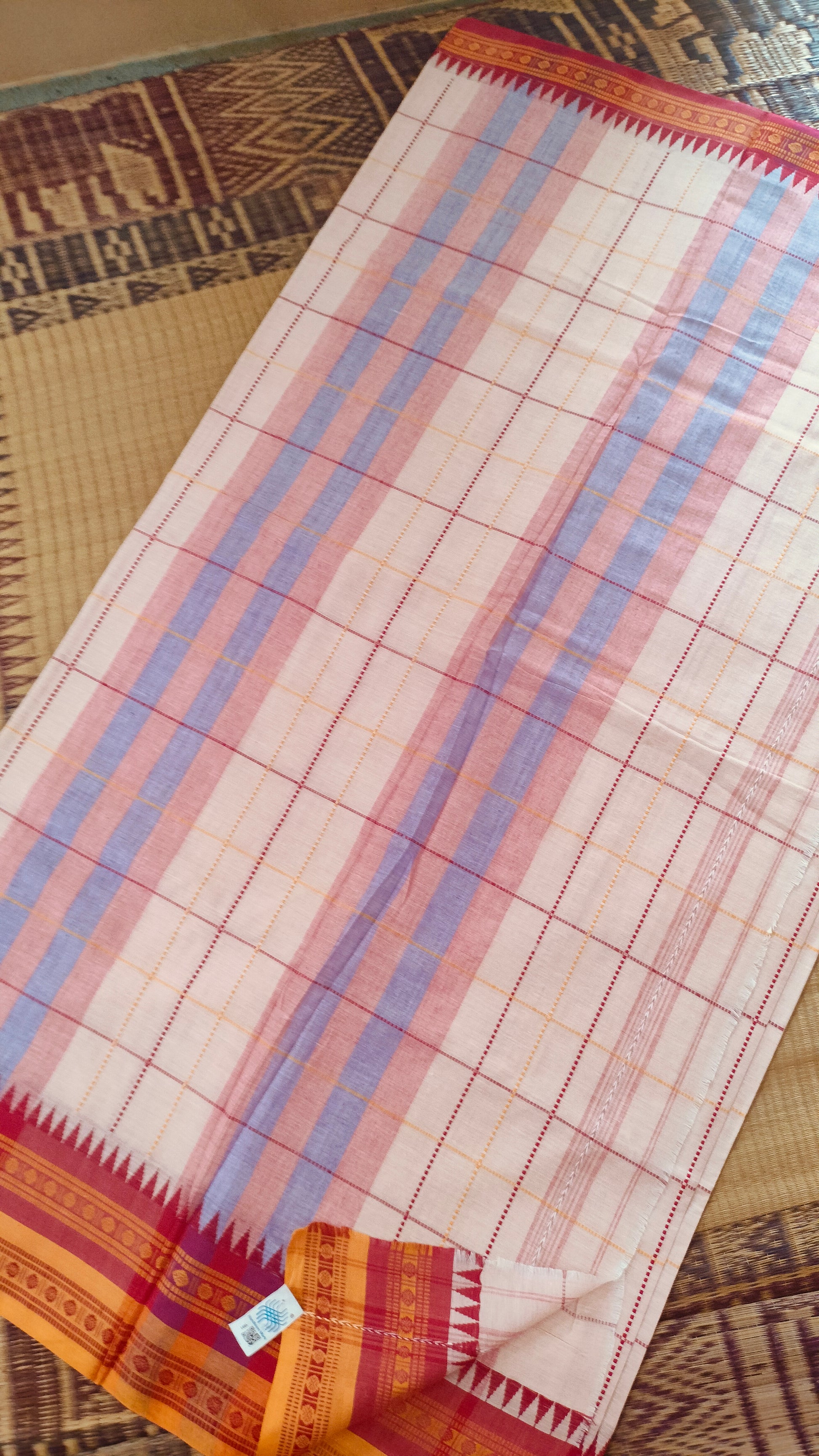 Off-white Dhonekhali handloom cotton saree with woven red and yellow check patterns throughout the body. Ideal for festive, semi-festive gatherings and refined everyday wear.