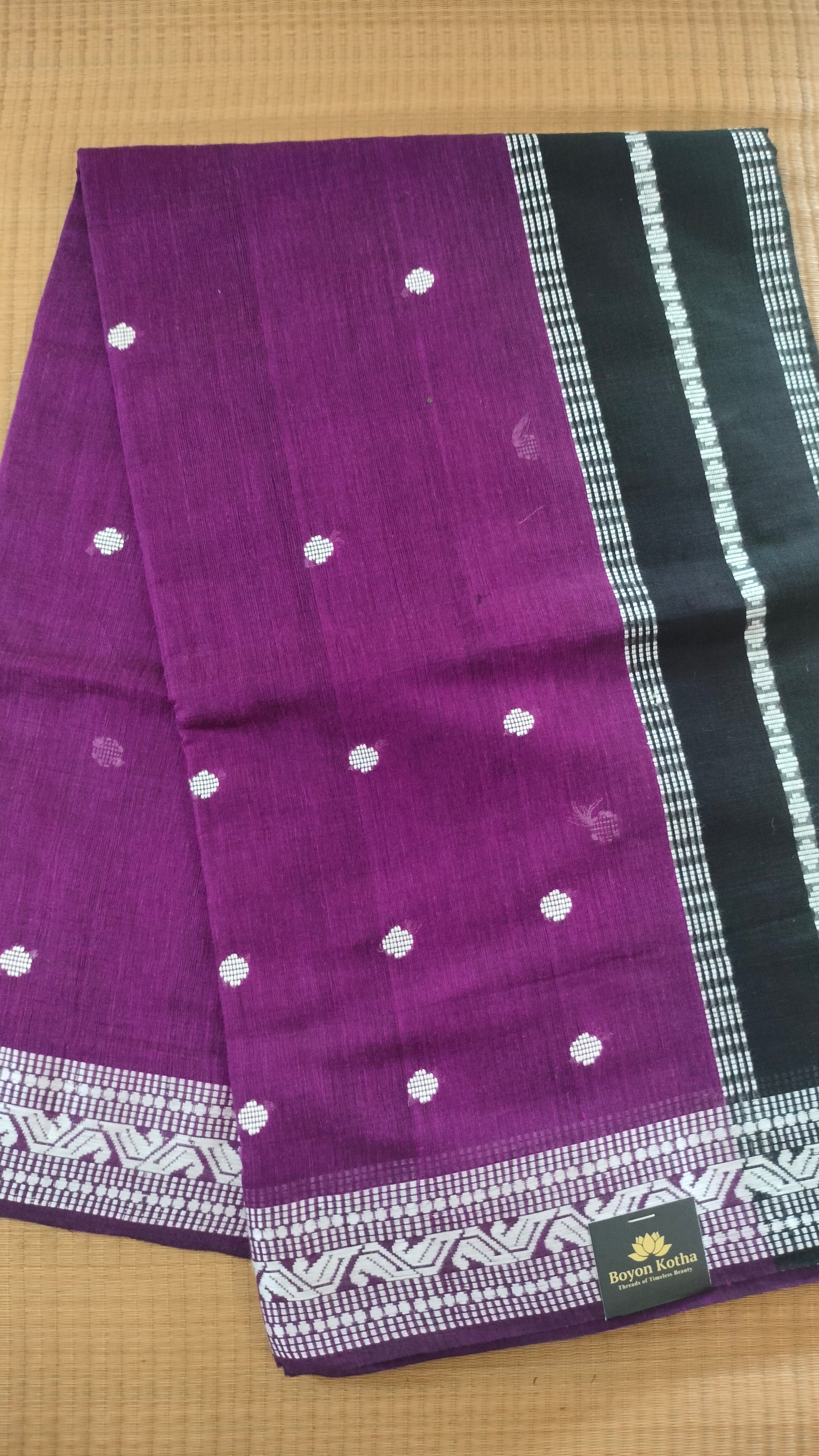 Purple Dhonekhali handloom cotton saree with woven white motifs across the body and the border with a black pallu that has woven white vertical stripes.