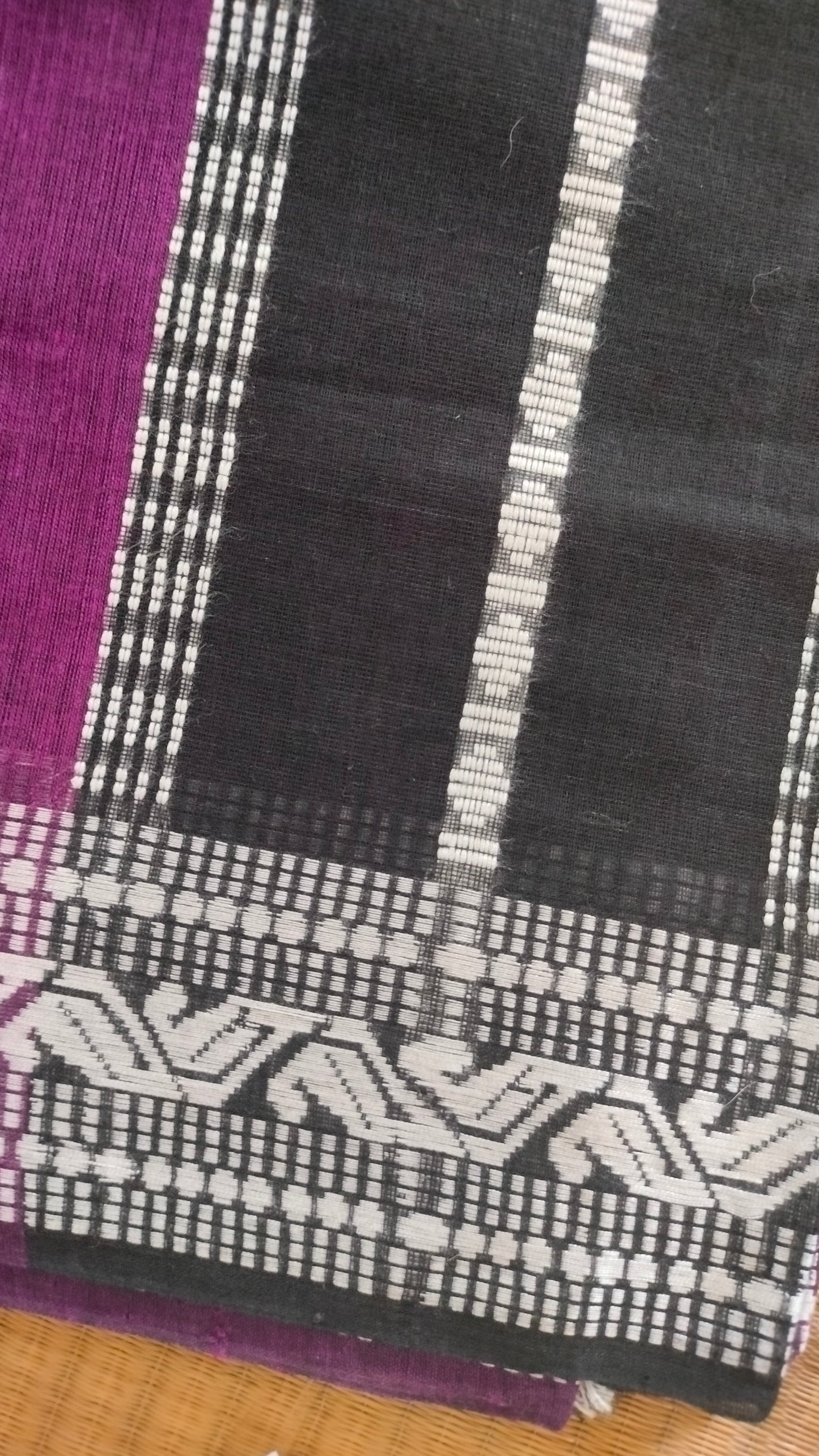 Purple Dhonekhali handloom cotton saree with woven white motifs across the body and the border with a black pallu that has woven white vertical stripes.