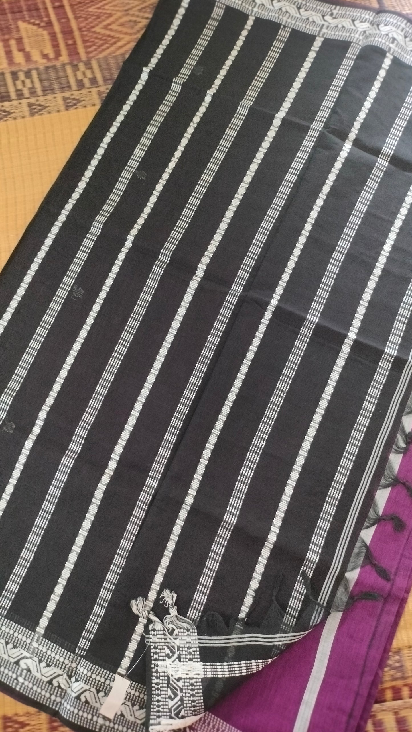 Purple Dhonekhali handloom cotton saree with woven white motifs across the body and the border with a black pallu that has woven white vertical stripes.