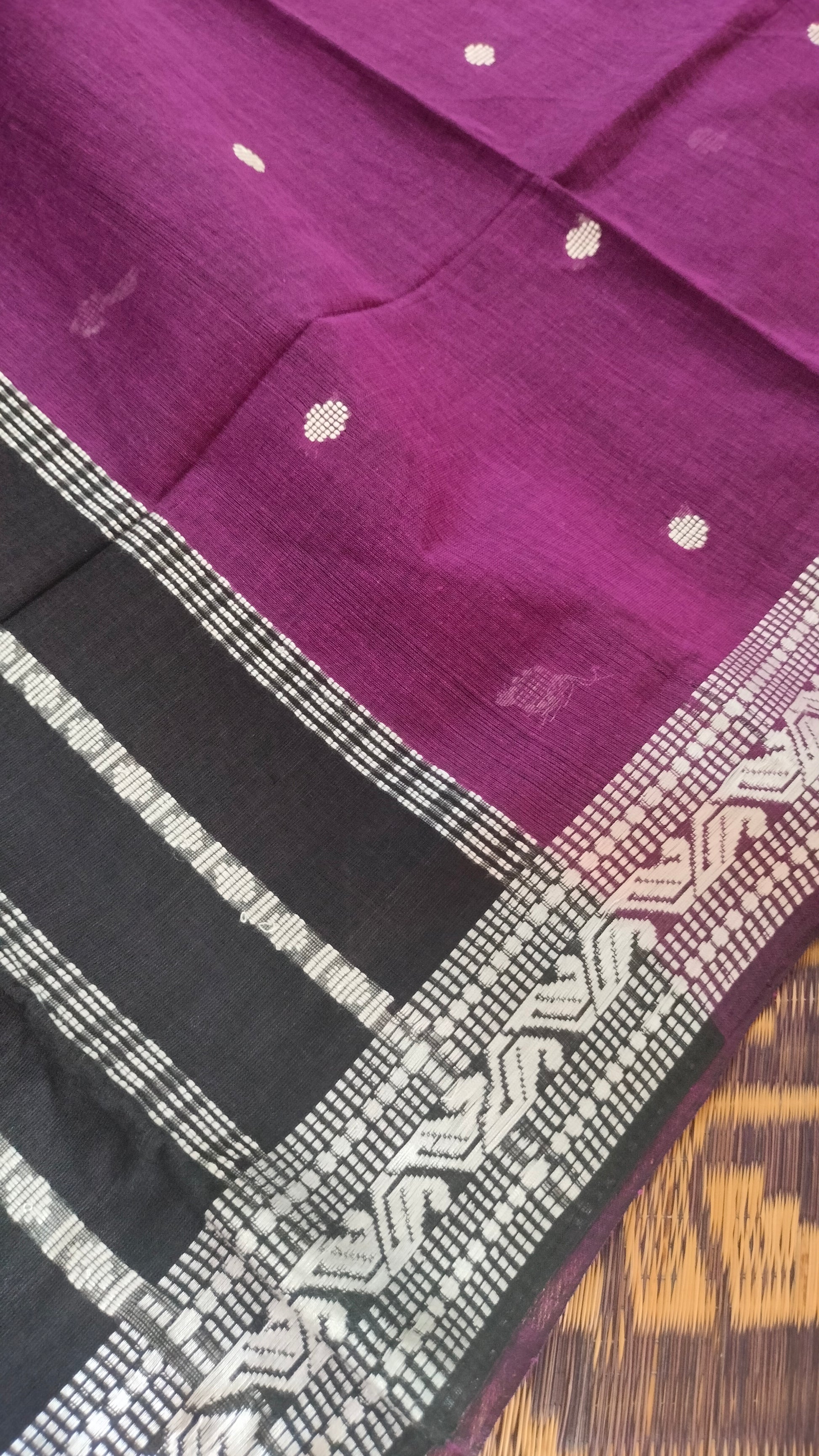 Purple Dhonekhali handloom cotton saree with woven white motifs across the body and the border with a black pallu that has woven white vertical stripes.