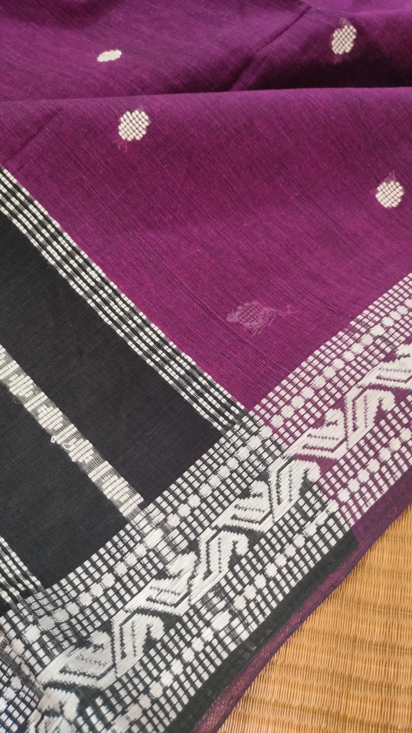 Purple Dhonekhali handloom cotton saree with woven white motifs across the body and the border with a black pallu that has woven white vertical stripes.