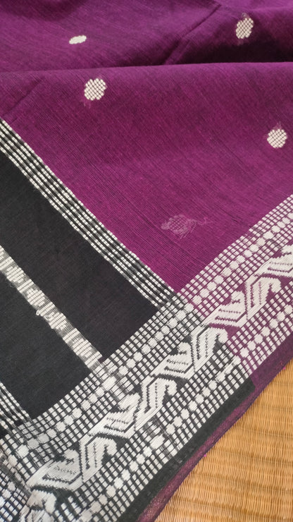Purple Dhonekhali handloom cotton saree with woven white motifs across the body and the border with a black pallu that has woven white vertical stripes.