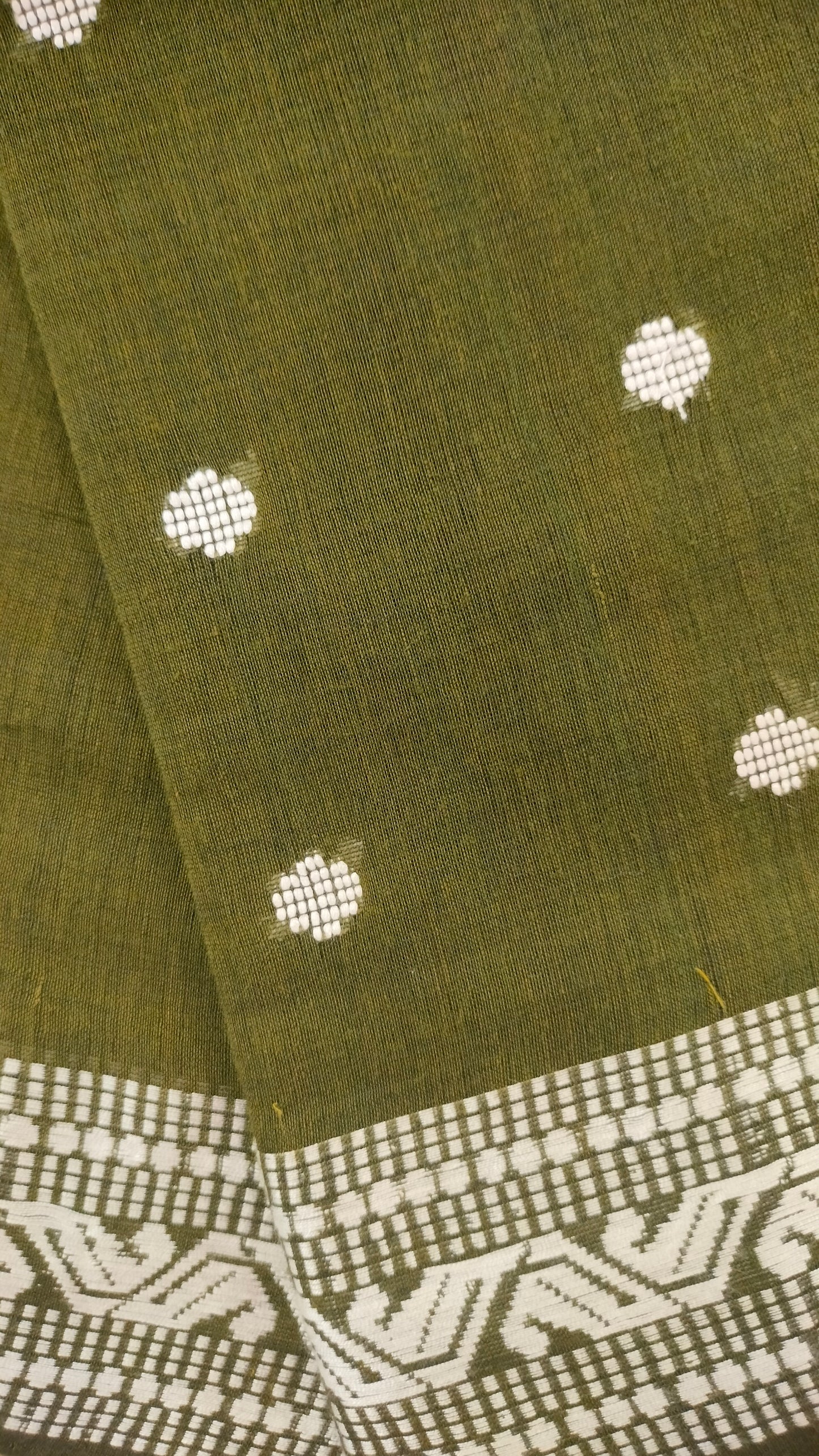 Olive Green Dhonekhali handloom cotton saree with woven white motifs across the body and the border with a black pallu that has woven white vertical stripes.