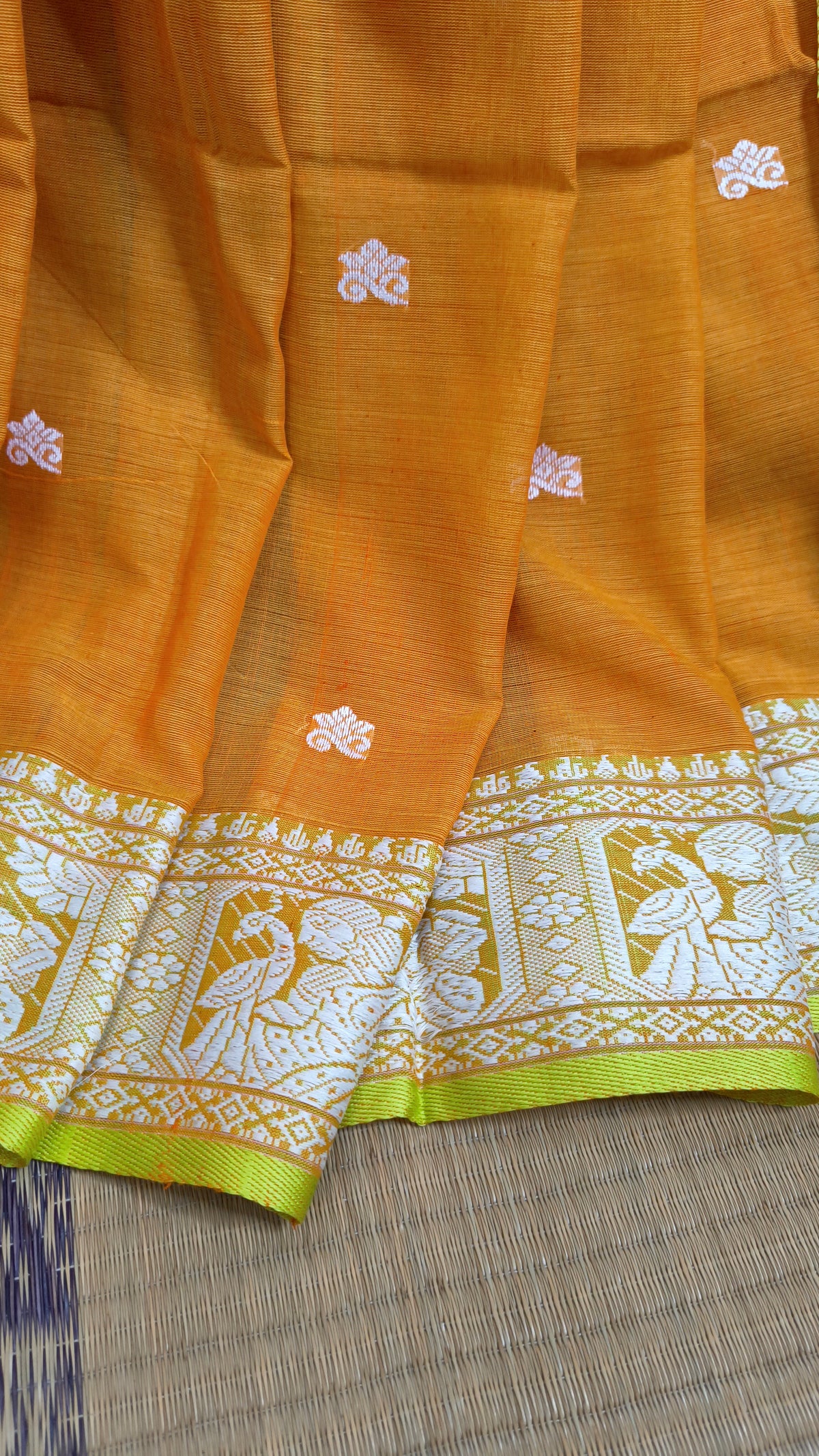 Orange cotton baluchari saree, with woven motifs in the border & pallu in white and neon green. Bengal handloom ideal for festivals & everyday celebrations.